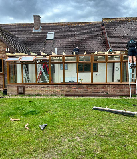 men working on the roof of a extension on a older roof tiled house