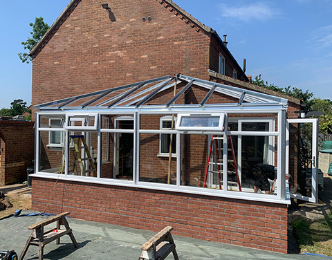 a conservatory being constructed as an extension onto a brick house